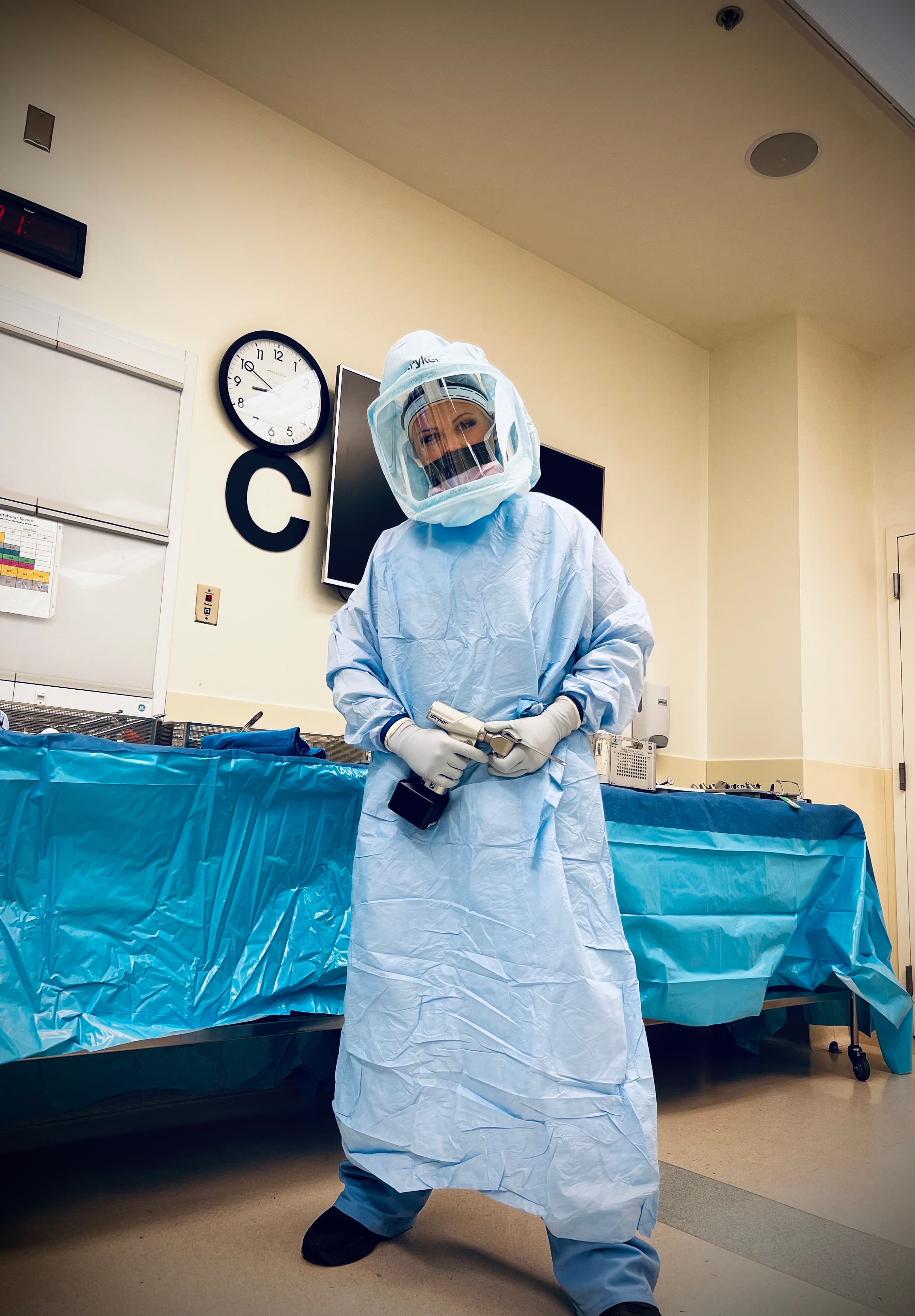 Sky wearing surgical PPE in an operating room, holding surgical instrumentation